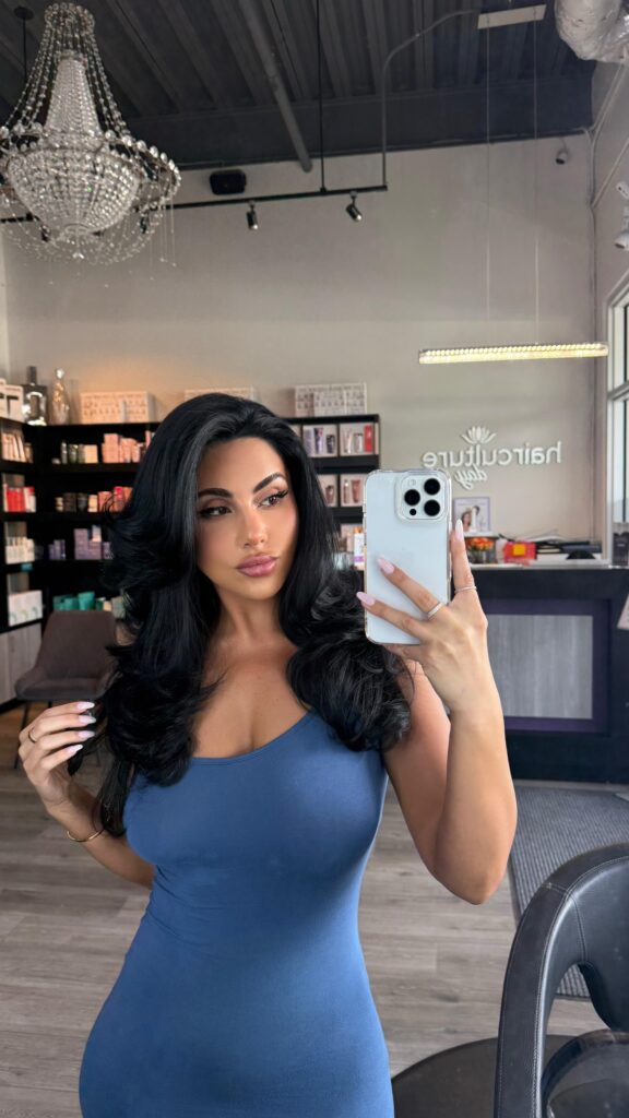 Client with fresh layered haircut and bouncy blowout taking a mirror selfie in the salon right after hair appointment at hair culture day spa, luxury salon in Pembroke Pines, FL